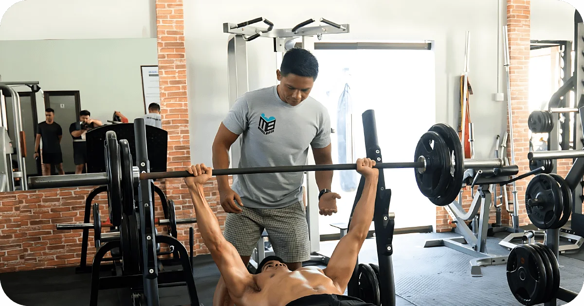 Trainer spotting bench press at Muscle Beach weight area