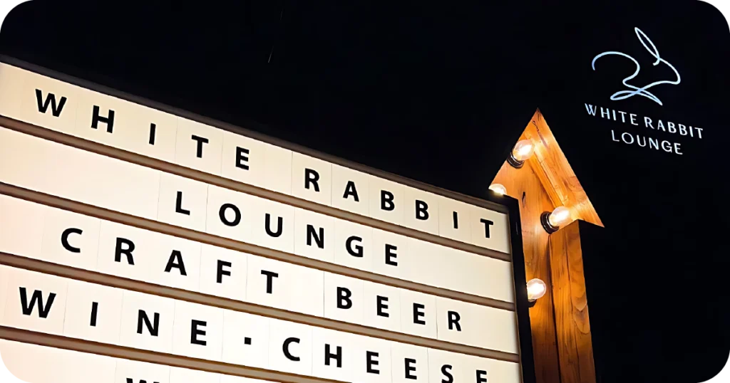 WHITE RABBIT LOUNGE lightbox sign with arrow at night