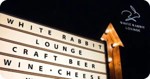 WHITE RABBIT LOUNGE lightbox sign with arrow at night