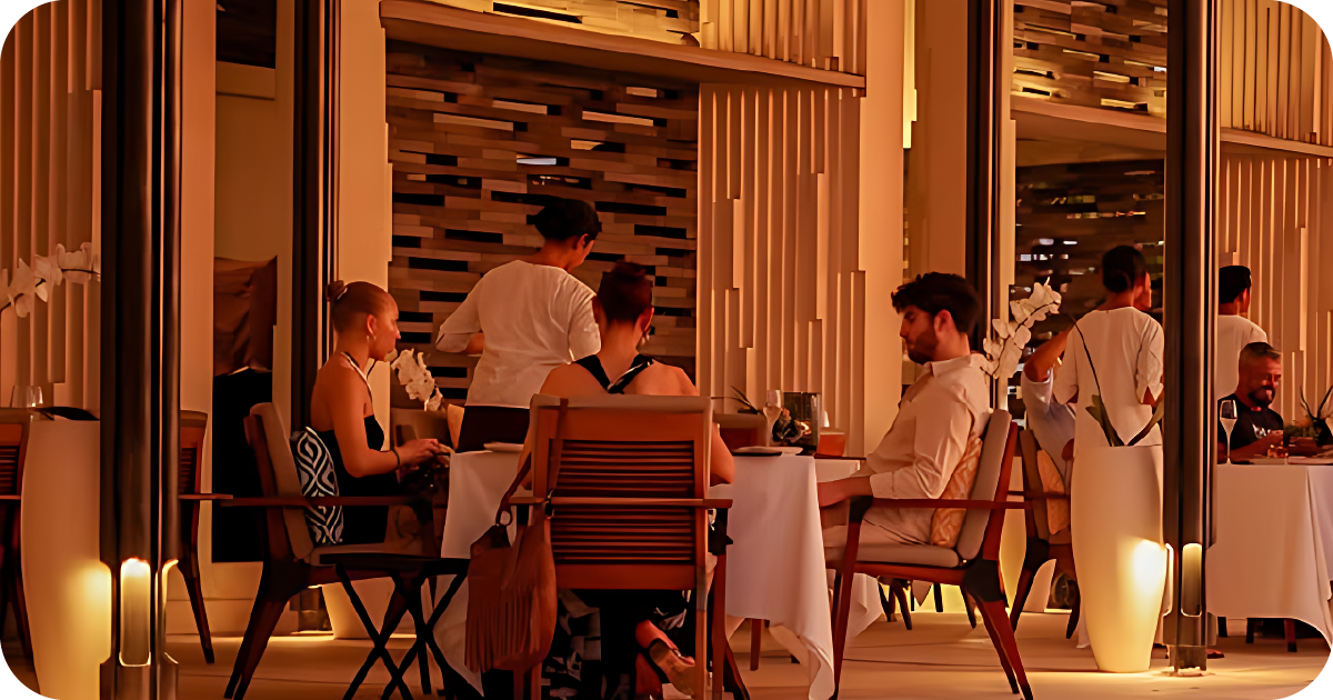 Warm, modern dining room with white tablecloths, orchids, and server