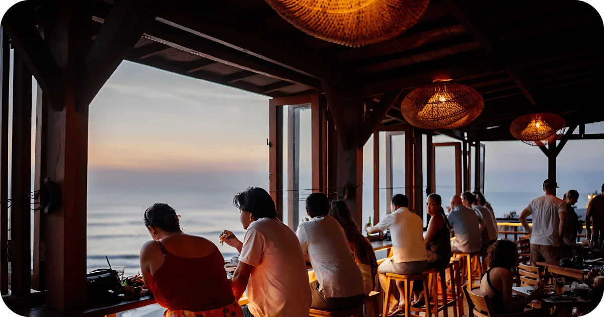 Warm sunset bar with woven pendant lights and ocean-facing stools
