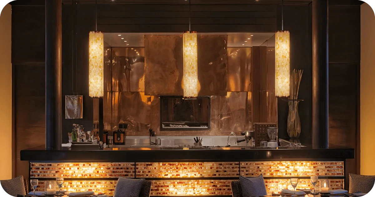 Warmly lit bar counter with backlit panels and pendant lights