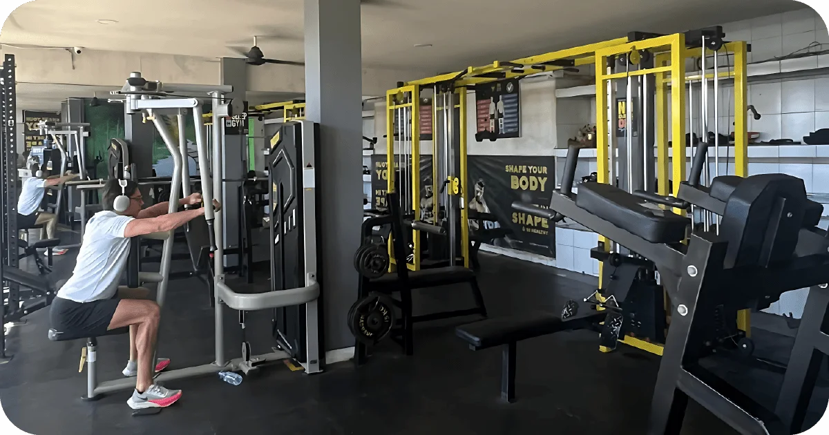Weight machines and cable stations in use, bench and plate storage