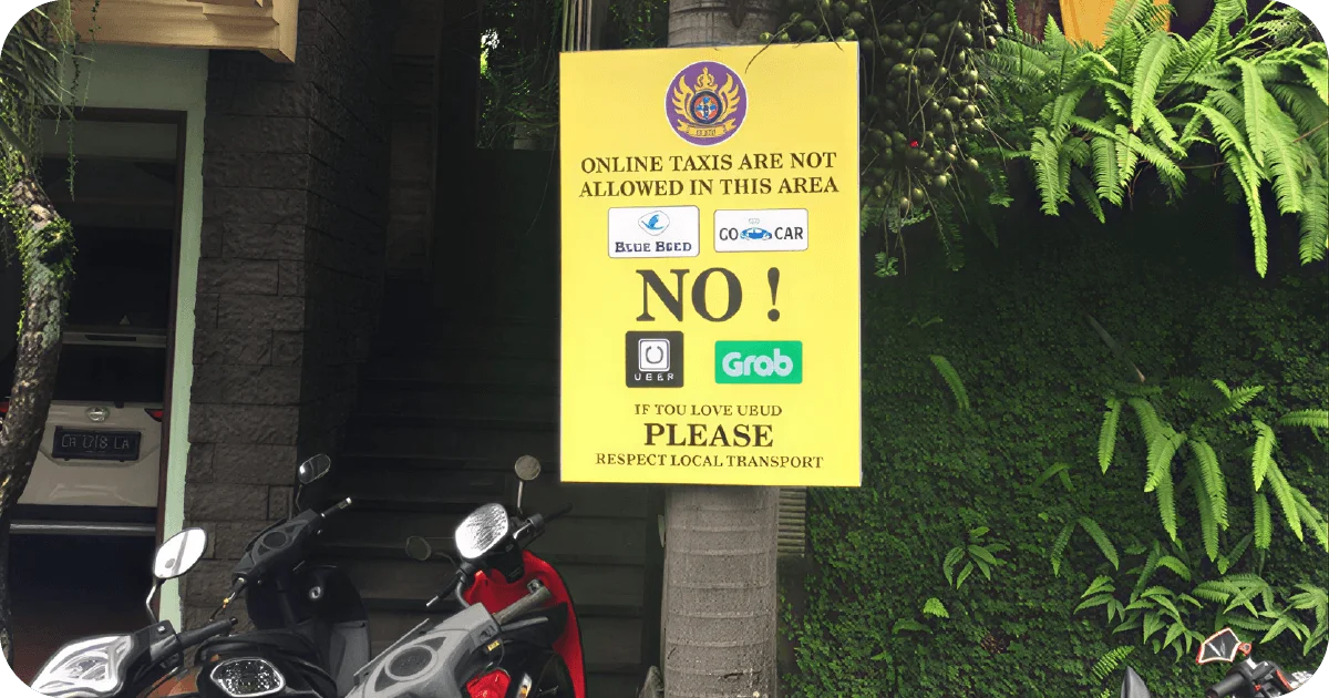 Yellow sign banning online taxis beside parked scooters