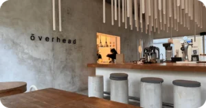 ōverhead concrete bar, espresso machines, cylindrical stools, ceiling tube lights