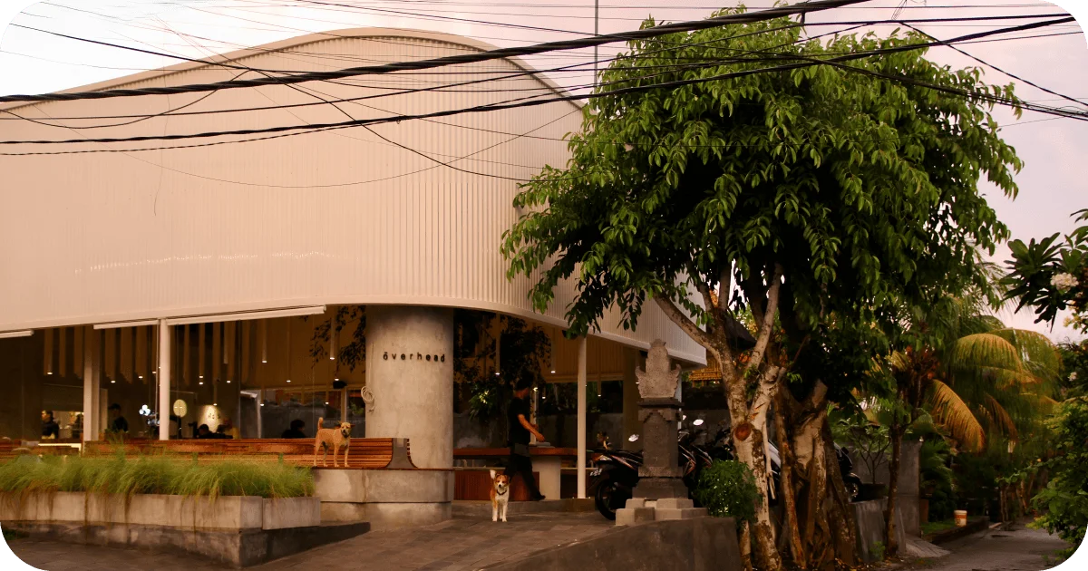 ōverhead curved white facade with street-side benches and evening glow