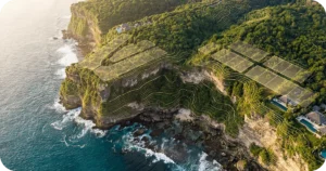 Aerial view of terraced seaside cliffs with forested hills and villas